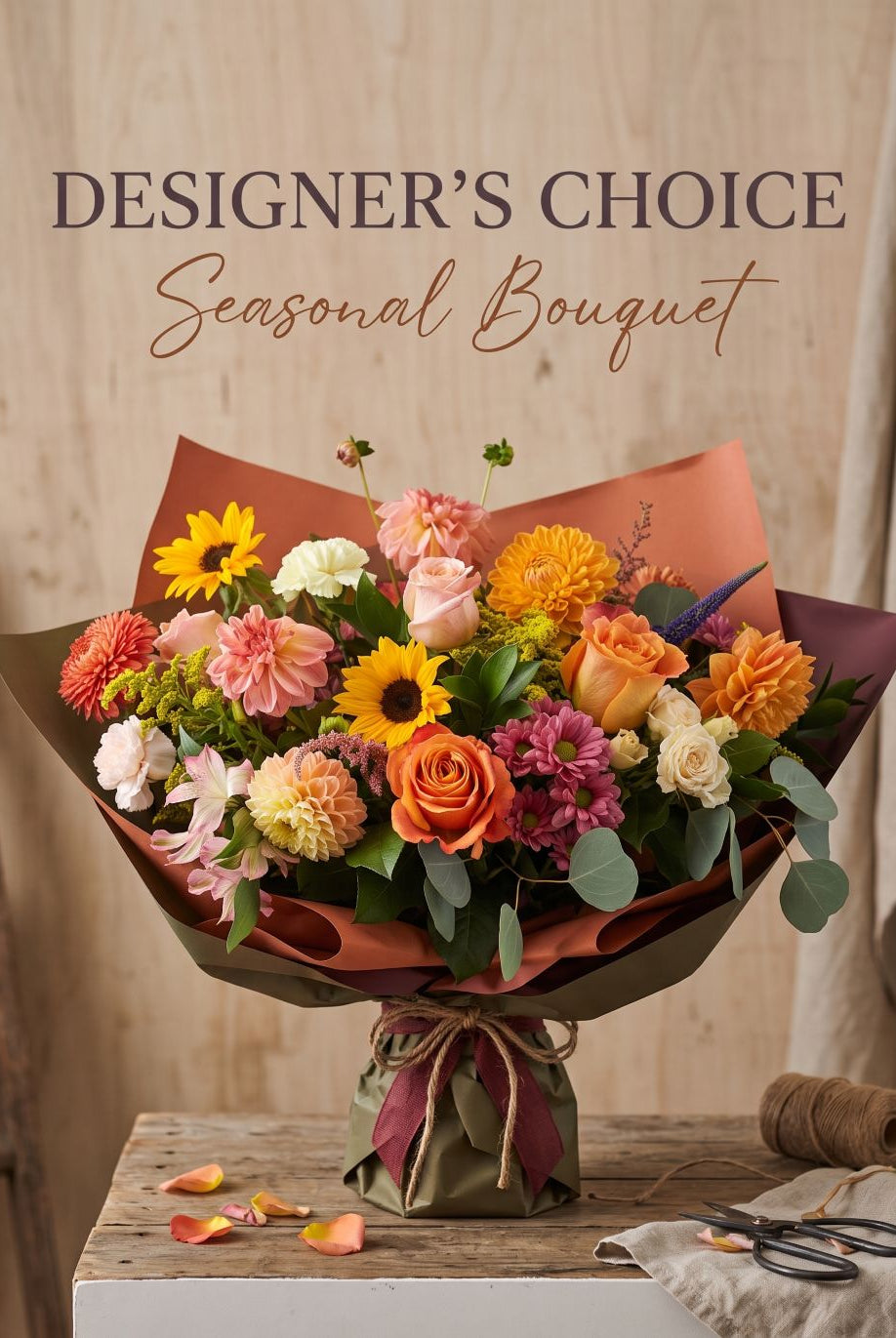 Designer's Choice Seasonal Bouquet: sunflowers, orange roses, peach dahlias and carnations wrapped in rust and olive paper with twine