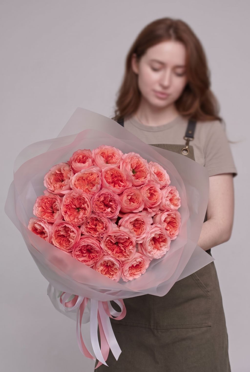 Florist holding a bouquet of coral-pink Candy Xpression garden roses wrapped in soft frosted paper