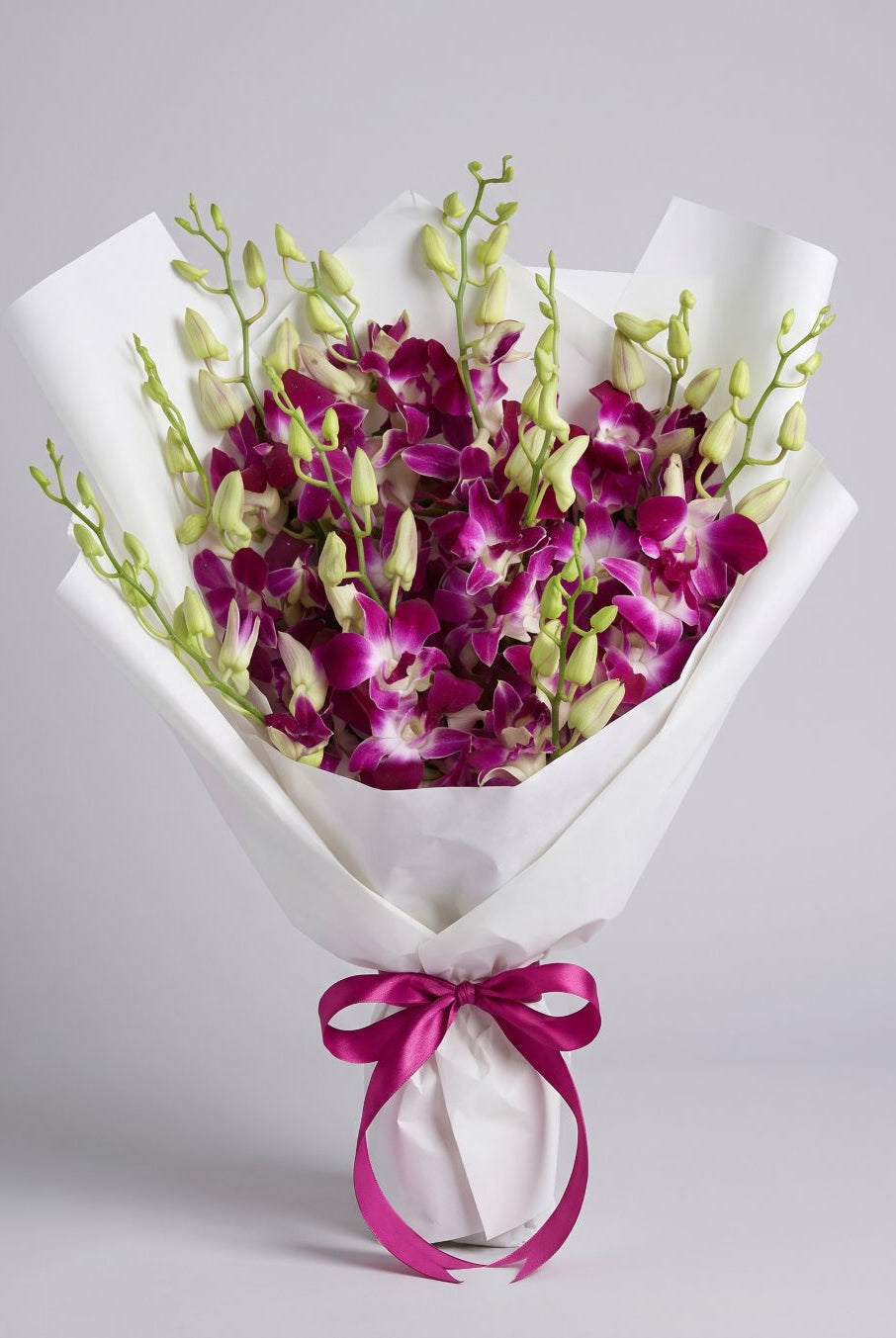 Pink Dendrobium Bouquet of magenta-pink dendrobium orchids with green buds wrapped in white paper with a fuchsia satin ribbon