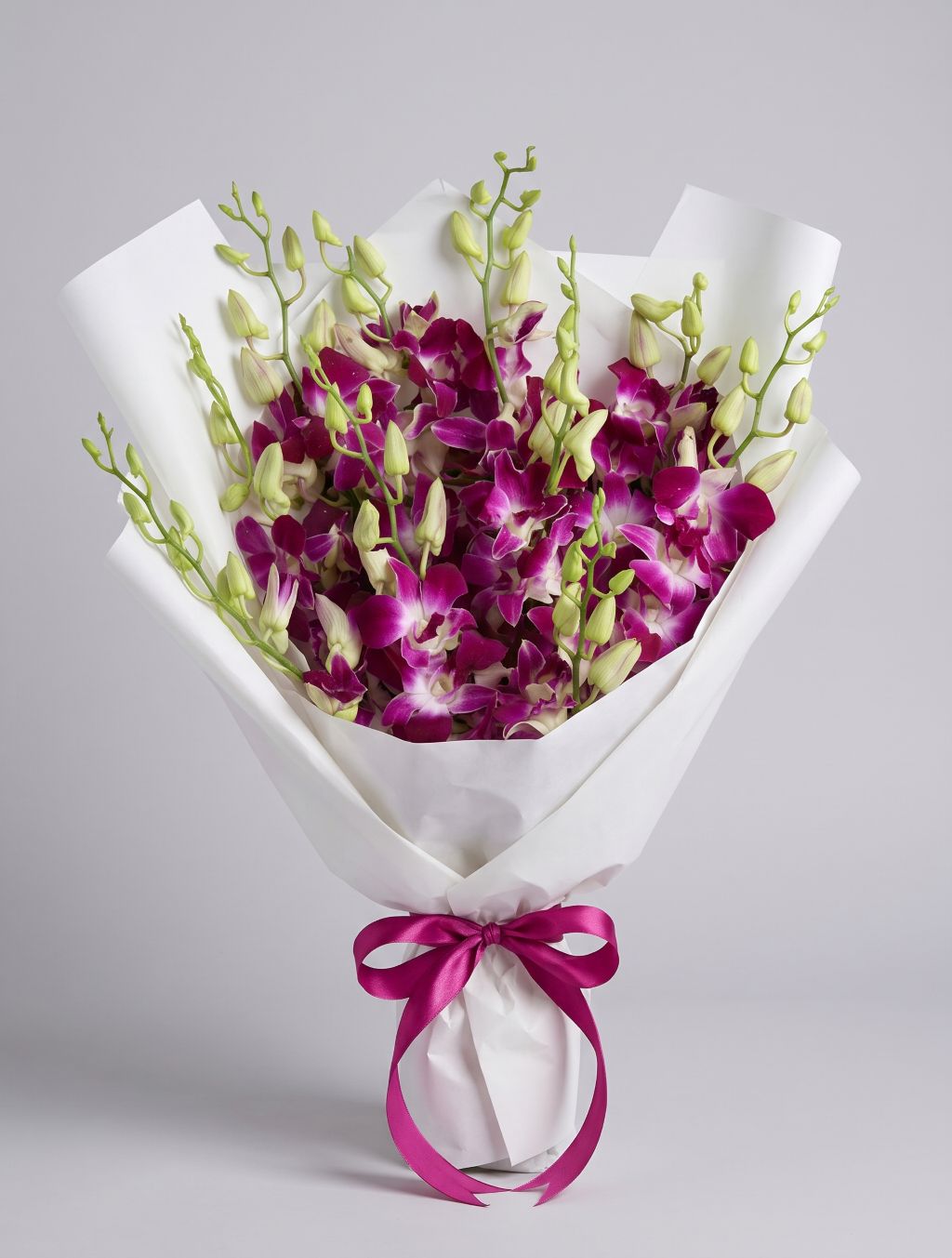 Pink Dendrobium Bouquet of magenta-pink dendrobium orchids with green buds wrapped in white paper with a fuchsia satin ribbon