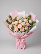 18 Pink Roses Bouquet of eighteen soft pink roses with baby’s breath, eucalyptus and greenery wrapped in pink and white paper with a pink satin ribbon
