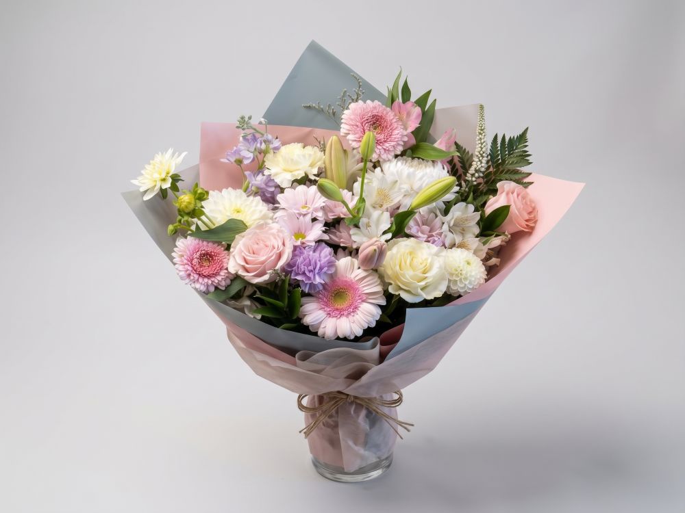 Pastel wrapped bouquet of pink gerberas, white lilies, cream roses, lavender carnations and alstroemeria in pink and blue paper