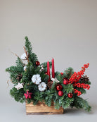 Decorative Christmas arrangement with greenery, red berries, and candles.