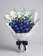 Blue Dendrobium Bouquet of blue and violet dendrobium orchids with turquoise buds wrapped in white paper with a navy satin ribbon