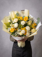 Designer’s choice fall bouquet of white roses, yellow gerbera daisies, yellow button mums, cream stock, white alstroemeria, solidago and eucalyptus wrapped in pale yellow and white paper