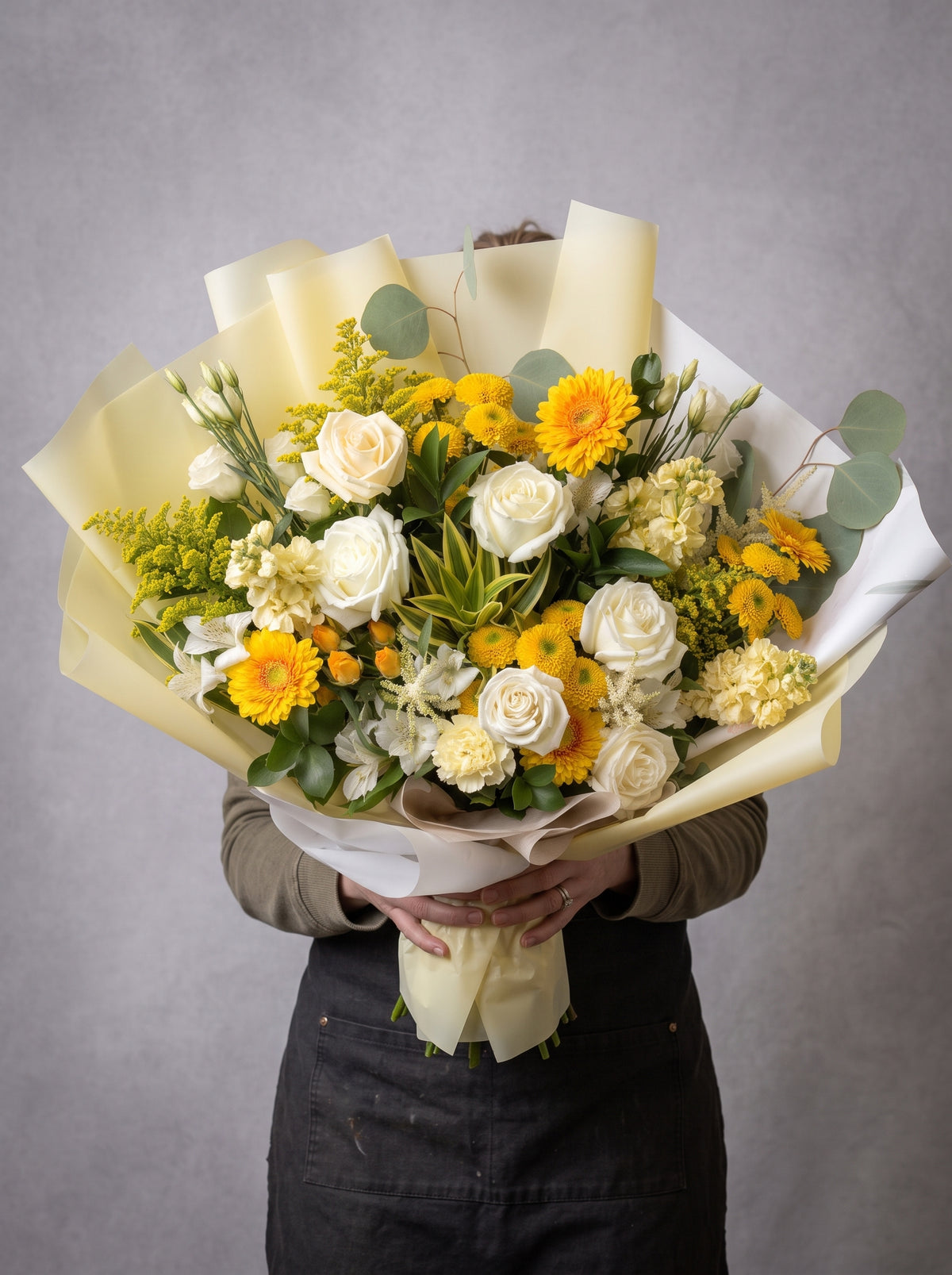 Designer’s choice fall bouquet of white roses, yellow gerbera daisies, yellow button mums, cream stock, white alstroemeria, solidago and eucalyptus wrapped in pale yellow and white paper