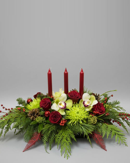 Festive Christmas Centerpiece with red roses and evergreen on a traditional holiday table setting.