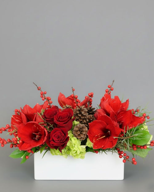 Holiday Glamour arrangement with red roses & amaryllis with lime-green accents as a luxurious Christmas table centerpiece."