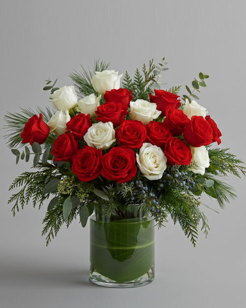 Bouquet of red and white roses in a clear vase on a gray background