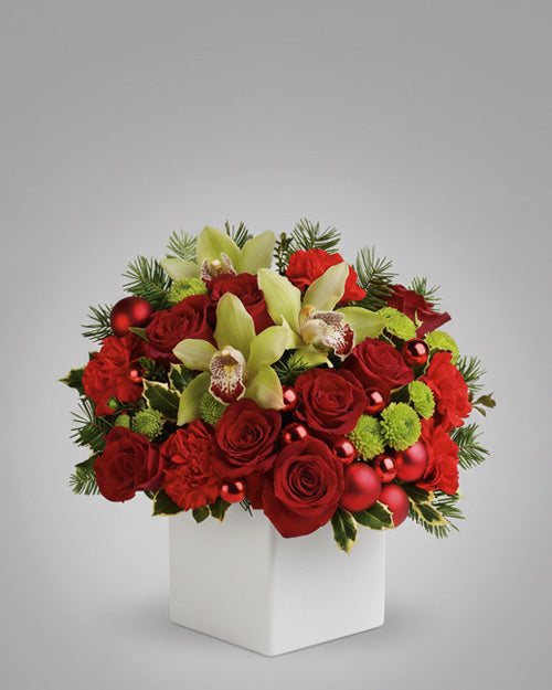 Bouquet of red roses, green orchids, and red ornaments in a white box on a gray background