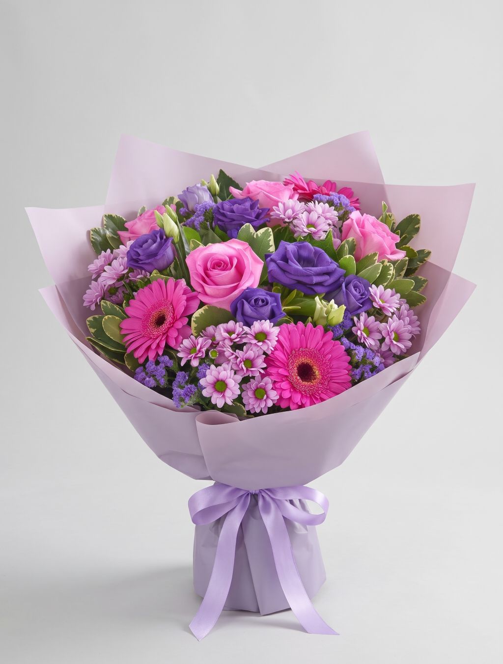 Seasonal Pinks & Purples Bouquet of hot pink roses, pink gerbera daisies, purple lisianthus, lavender daisy mums and purple statice wrapped in lavender paper with a lavender ribbon
