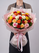 Sunset Fiesta Roses bouquet of mixed red, pink, peach, orange, yellow and white roses wrapped in clear cellophane with pink ribbon