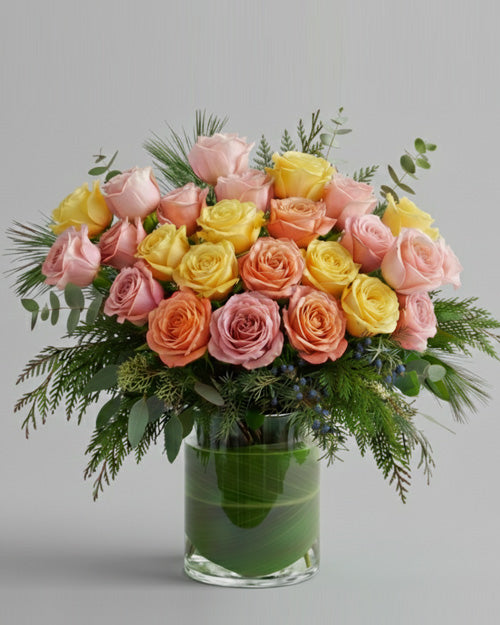 Bouquet of pink, yellow, and orange roses in a clear vase on a gray background