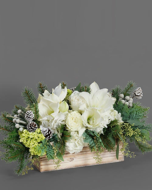Floral centerpiece with white flowers and greenery designed in a wooden box.