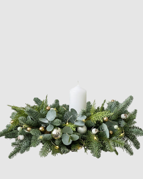 Decorative greenery arrangement with a candle on a white background