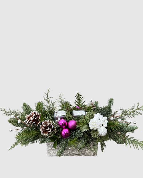 Decorative Christmas arrangement with greenery, pinecones, and ornaments on a white background
