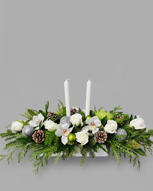 Decorative floral arrangement with candles and ornaments on a gray background