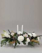 Floral arrangement with white candles on a gray background