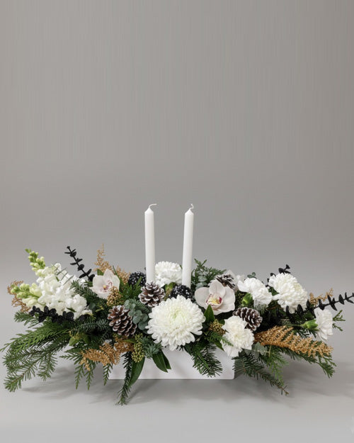 Floral arrangement with white candles on a gray background