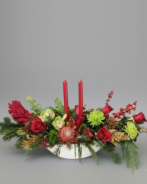 Decorative floral arrangement with red candles on a gray background